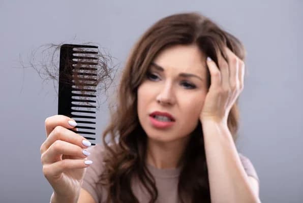 Doctor examining a patient's scalp during a hair fall consultation at The Aesthetic Edge