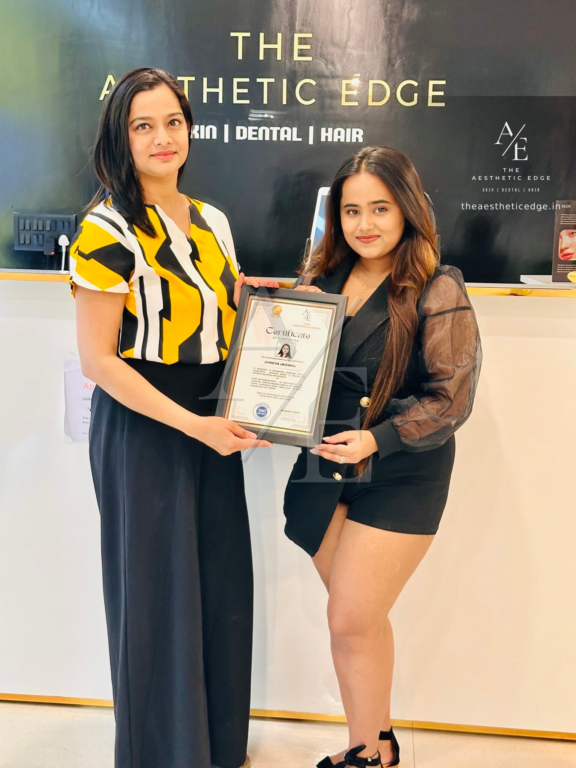 An academy graduate holding her framed Aesthetic Edge certificate of completion at the clinic reception